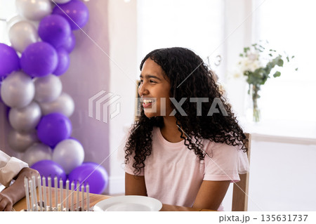 Smiling girl celebrating religious event with family, surrounded by festive balloons 135631737