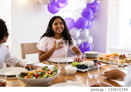 Smiling girl expressing gratitude at family celebration with food and decorations Smiling girl expressing gratitude at family celebration with food and decorations 135631749