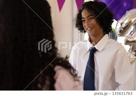Teen boy in white shirt and tie smiling during festive celebration indoors Teen boy in white shirt and tie smiling during festive celebration indoors 135631763