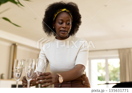 Woman setting table with champagne glasses at home, preparing for gathering 135631771