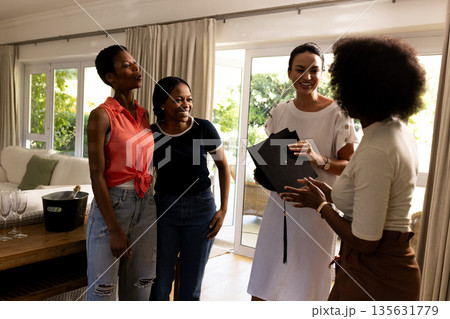 Group of female friends laughing and chatting at home, enjoying each other's company Group of female friends laughing and chatting at home, enjoying each other's company 135631779