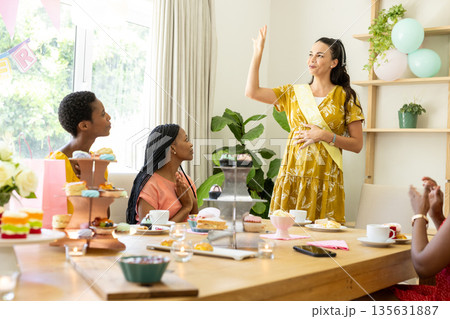 Celebrating at home, diverse female friends enjoying baby shower with desserts 135631887