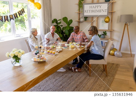 Senior friends enjoying retirement celebration with snacks and drinks at home Senior friends enjoying retirement celebration with snacks and drinks at home 135631946