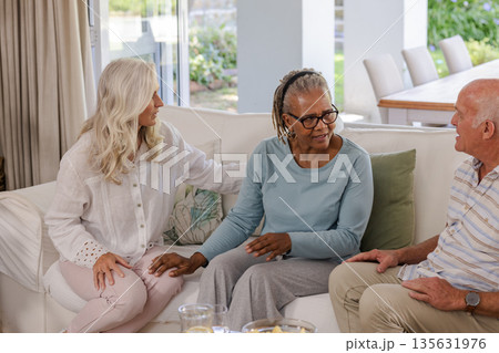 Senior friends sitting on sofa at home, enjoying conversation and companionship Senior friends sitting on sofa at home, enjoying conversation and companionship 135631976