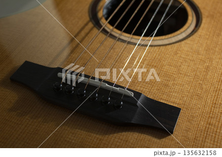 This is a close-up of the strings of an acoustic guitar. 135632158