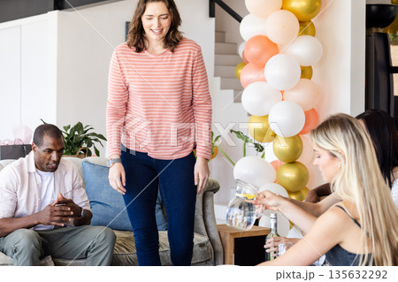 Friends enjoying casual gathering at home with balloons and refreshments 135632292