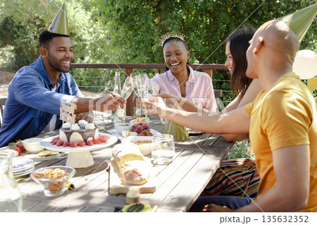 Celebrating outdoors, friends toasting with champagne at festive party together 135632352