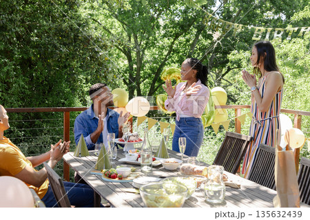 Friends celebrating birthday outdoors with balloons and decorations, enjoying moment 135632439