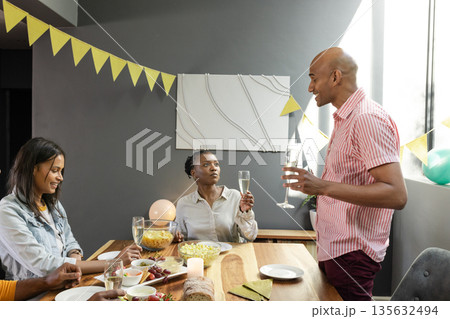 Celebrating at home, African American friends raising glasses and having conversation Celebrating at home, African American friends raising glasses and having conversation 135632494