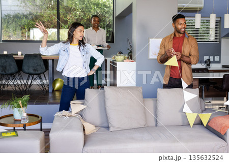 Decorating living room with bunting, friends feeling excited for celebration Decorating living room with bunting, friends feeling excited for celebration 135632524