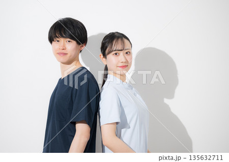 白背景の爽やかな看護師イメージの若い男女　新卒採用や転職の求人などにカメラ目線	 135632711