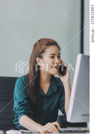 Determined asian businesswoman works late in a modern office, confidently analyzing data on her laptop, embodying success and professionalism with a smile Determined asian businesswoman works late in a modern office, confidently analyzing data on her laptop, embodying success and professionalism with a smile 135632863