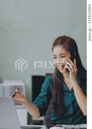 Determined asian businesswoman works late in a modern office, confidently analyzing data on her laptop, embodying success and professionalism with a smile Determined asian businesswoman works late in a modern office, confidently analyzing data on her laptop, embodying success and professionalism with a smile 135632864