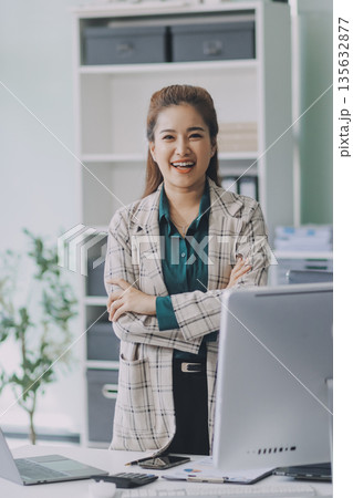 Determined asian businesswoman works late in a modern office, confidently analyzing data on her laptop, embodying success and professionalism with a smile Determined asian businesswoman works late in a modern office, confidently analyzing data on her laptop, embodying success and professionalism with a smile 135632877