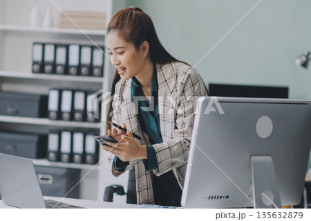 Determined asian businesswoman works late in a modern office, confidently analyzing data on her laptop, embodying success and professionalism with a smile Determined asian businesswoman works late in a modern office, confidently analyzing data on her laptop, embodying success and professionalism with a smile 135632879