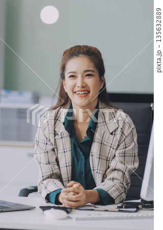 Cheerful business lady working on laptop in office, Asian happy beautiful businesswoman in formal suit work in workplace. Attractive female employee office worker smile. Cheerful business lady working on laptop in office, Asian happy beautiful businesswoman in formal suit work in workplace. Attractive female employee office worker smile. 135632889