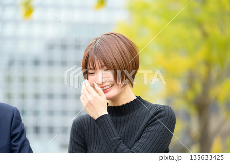 オフィス街で笑顔で会話をする男女 オフィス街で笑顔で会話をする男女 135633425