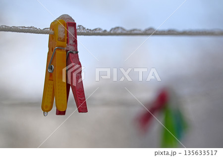 A red and yellow clothespin is hanging on a line A red and yellow clothespin is hanging on a line 135633517