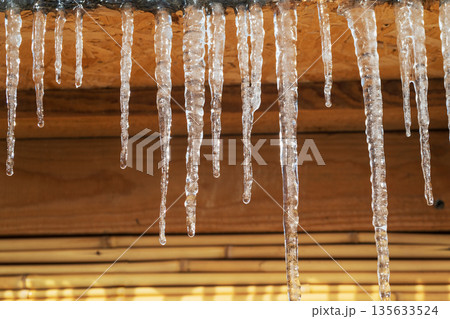 Icicles hanging from a roof, they are clear and shiny Icicles hanging from a roof, they are clear and shiny 135633524