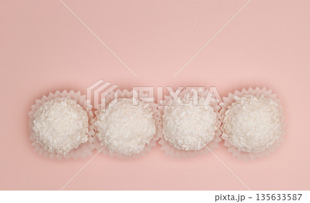 Four white pastries in paper cups on a pink background Four white pastries in paper cups on a pink background 135633587