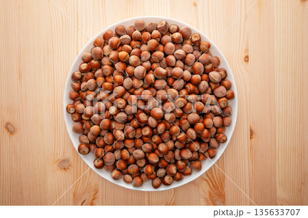 A plate of nuts is on a wooden table 135633707