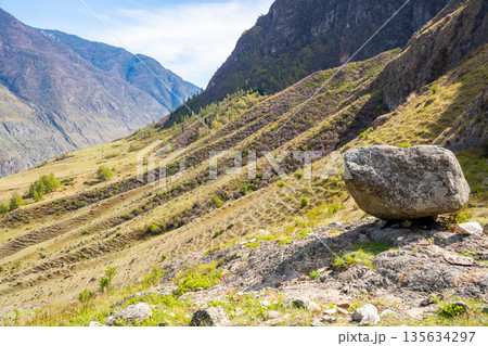 Black stone boulder on mountain with view of Chulyshman valley Altai Russia Sacred natural landmark and spiritual site 135634297