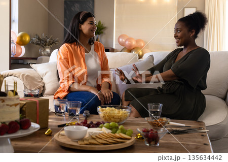 African American woman and friend enjoying conversation at home during celebration African American woman and friend enjoying conversation at home during celebration 135634442
