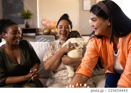 Celebrating at home, diverse friends enjoying birthday with cake and baby 135634443