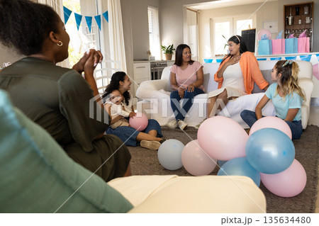 Celebrating baby shower, friends with balloons and gifts sharing joyful conversation Celebrating baby shower, friends with balloons and gifts sharing joyful conversation 135634480