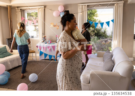 Family celebrating baby shower at home with balloons and snacks, enjoying together Family celebrating baby shower at home with balloons and snacks, enjoying together 135634538