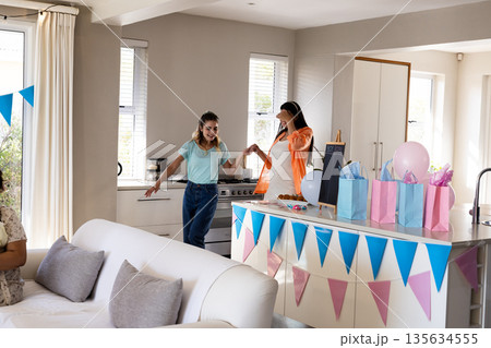 Celebrating at home, friends holding hands and smiling near decorated kitchen counter Celebrating at home, friends holding hands and smiling near decorated kitchen counter 135634555