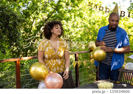 Friends decorating with balloons, celebrating birthday outdoors on sunny day Friends decorating with balloons, celebrating birthday outdoors on sunny day 135634600