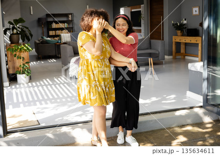 Friends laughing and enjoying sunny day at home, embracing and smiling warmly Friends laughing and enjoying sunny day at home, embracing and smiling warmly 135634611