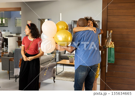 African American couple hugging with balloons and gift at home celebration 135634665