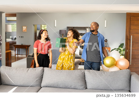 At home, friends celebrating with gifts and balloons, smiling together happily 135634699