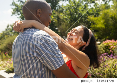 Couple embracing outdoors, smiling and enjoying sunny day in garden 135634726