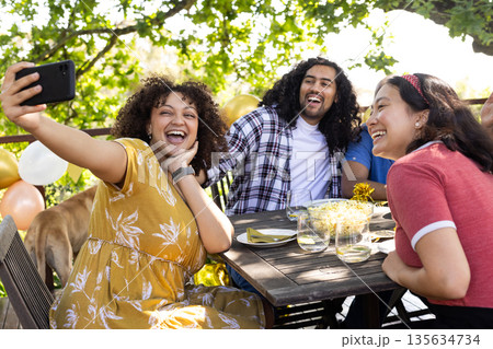 Friends taking selfie at outdoor party, smiling and enjoying festive celebration Friends taking selfie at outdoor party, smiling and enjoying festive celebration 135634734