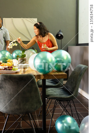 Woman decorating table with balloons and flowers, preparing for celebration at home 135634758