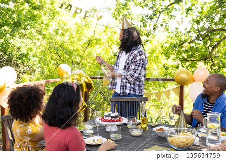 Celebrating outdoor birthday party, diverse friends with cake and champagne together 135634759