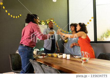 Celebrating at home, friends toasting drinks with joyful smiles and laughter Celebrating at home, friends toasting drinks with joyful smiles and laughter 135634773