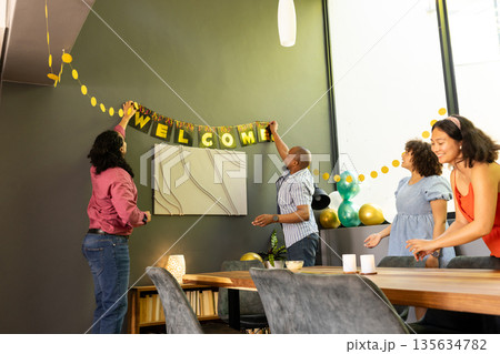 Friends decorating room with welcome banner and balloons for celebration Friends decorating room with welcome banner and balloons for celebration 135634782