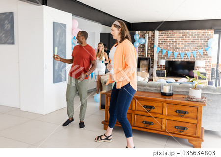 Friends celebrating at home, enjoying drinks and conversation in festive living room Friends celebrating at home, enjoying drinks and conversation in festive living room 135634803