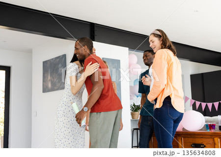 Friends celebrating together at home, sharing hugs and laughter in living room Friends celebrating together at home, sharing hugs and laughter in living room 135634808