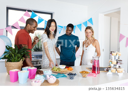 Friends enjoying snacks and drinks at home during festive celebration Friends enjoying snacks and drinks at home during festive celebration 135634815