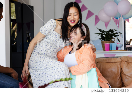 Friends celebrating at home, laughing and enjoying festive decorations and balloons 135634839