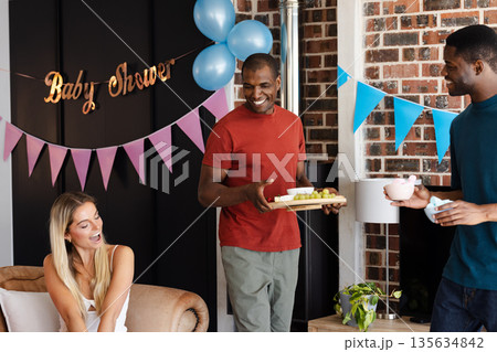 Friends celebrating baby shower with snacks and drinks, enjoying joyful conversation 135634842