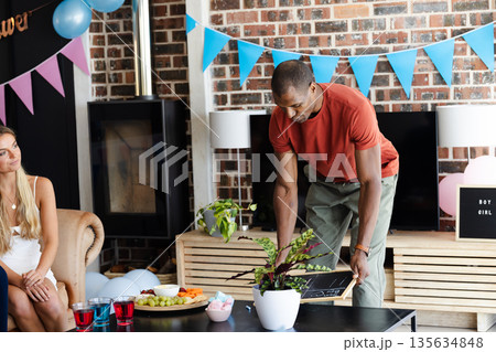 African American man preparing party decorations at home with snacks and drinks African American man preparing party decorations at home with snacks and drinks 135634848