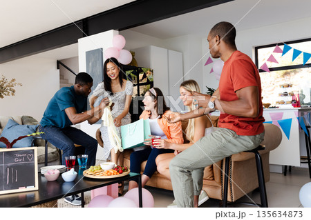 Friends celebrating at home, exchanging gifts and enjoying snacks together 135634873