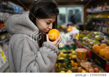 Woman Holds Orange in Market Surrounded by Various Fruits and Vegetables During Daytime 135635088