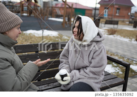 Close Friends Talk and Enjoy Warm Drinks in a Park During Winter Afternoon Close Friends Talk and Enjoy Warm Drinks in a Park During Winter Afternoon 135635092